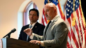 Blaise Ingoglia speaking next to Ron DeSantis in front of a U.S. flag.