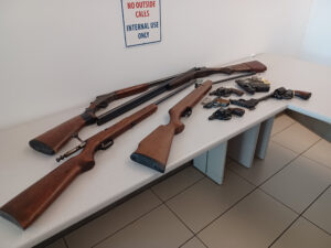 A variety of firearms strewn across a table.