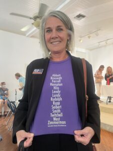 Flo Entler smiling and showing off a Sarasota School of Architecture shirt.