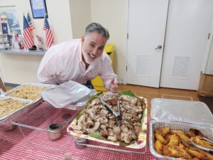 Joe Neunder smiling and giving a thumbs-up to a tray of food.
