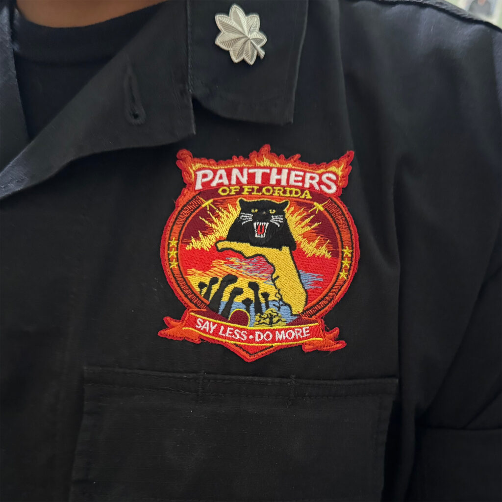 Close-up of a black button down with a Panthers of Florida emblem on the chest.