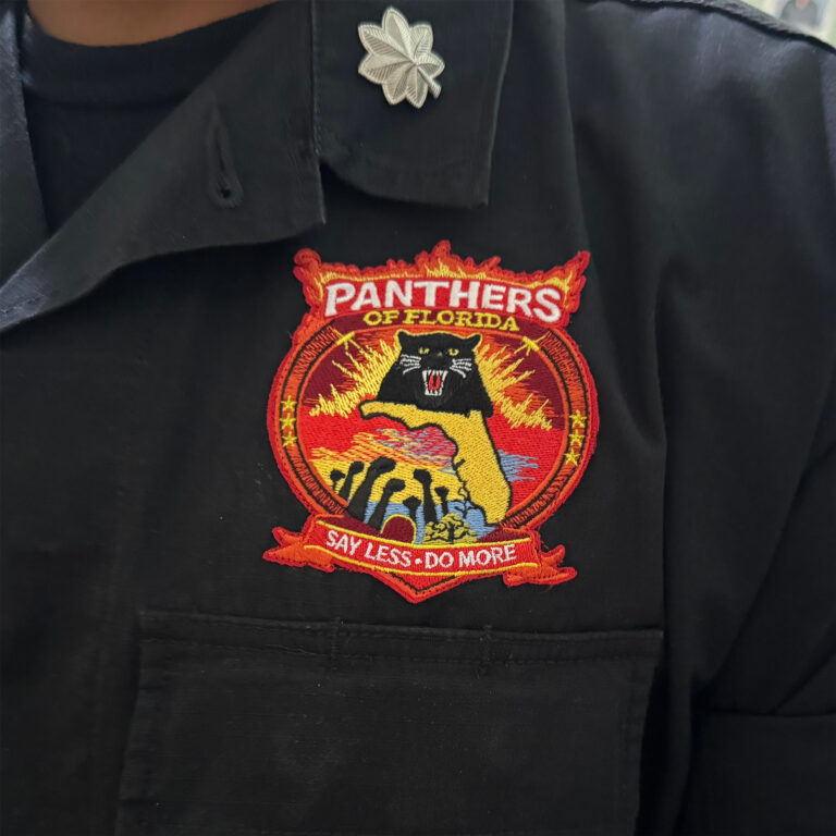Close-up of a black button down with a Panthers of Florida emblem on the chest.