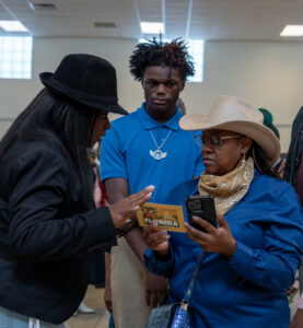 Tamika Lyles speaking to someone who holds a Florida postcard and a cell phone.