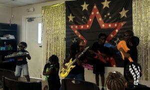 Students perform with inflatable musical instrument toys.