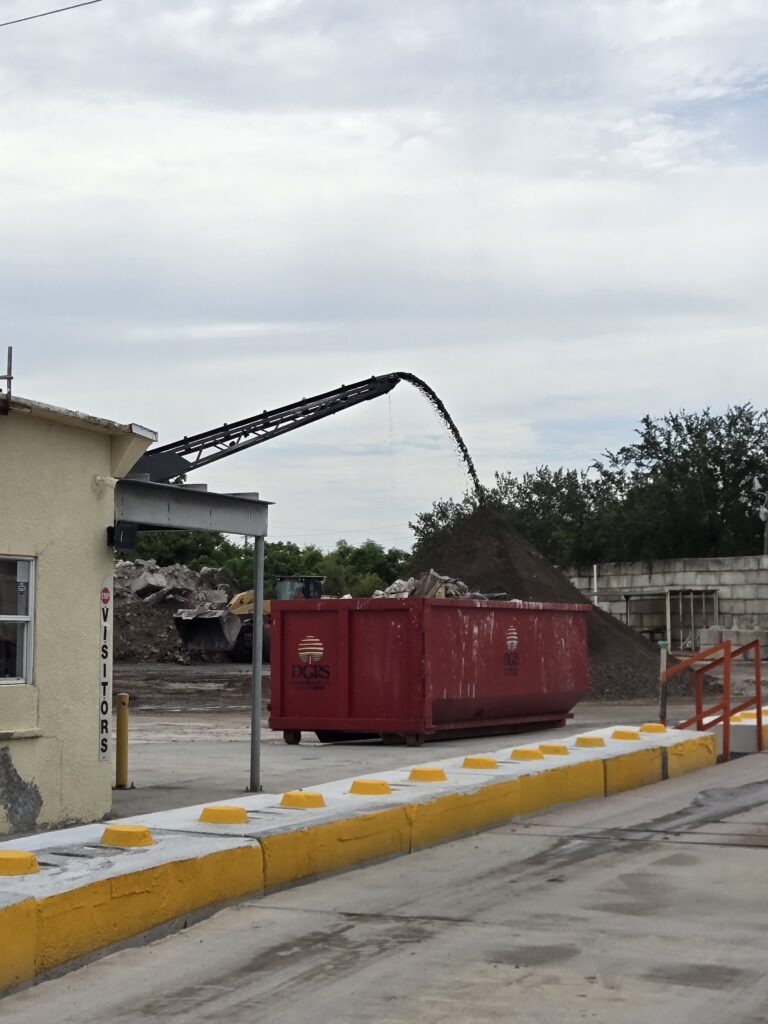 Crushed concrete being poured atop a huge dust pile.