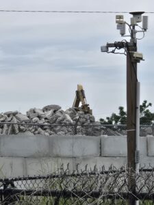 A pile of concrete fragments beyond a cinderblock wall.