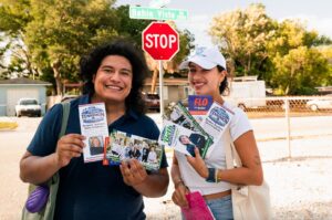Sebastian Martinez and Luna Reitz-Neto smile and hold flyers promoting Flo Entler, Beth Mayberry and Megan Tennimon.