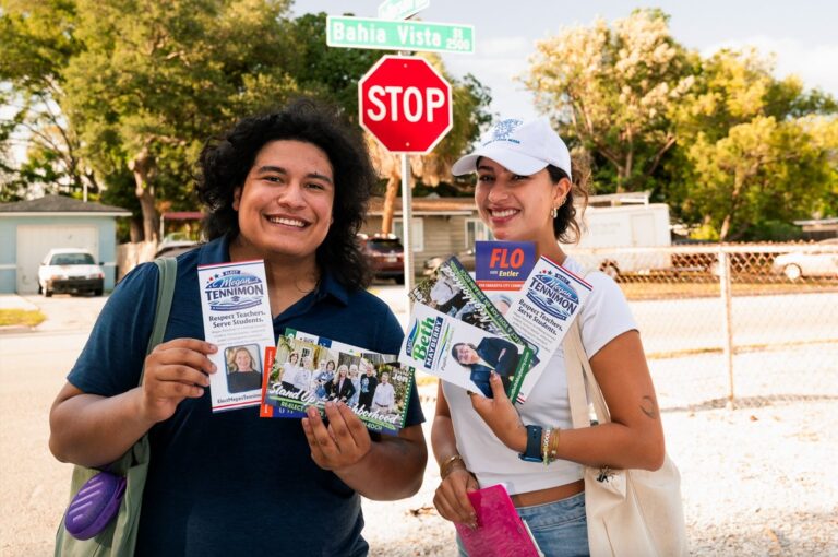 Sebastian Martinez and Luna Reitz-Neto smile and hold flyers promoting Flo Entler, Beth Mayberry and Megan Tennimon.