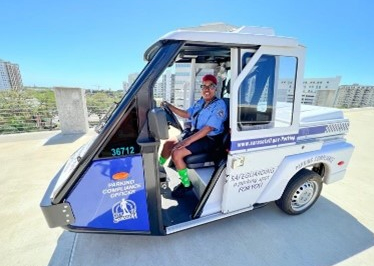 A driver in a City of Sarasota Parking Division vehicle smiling at the viewer.