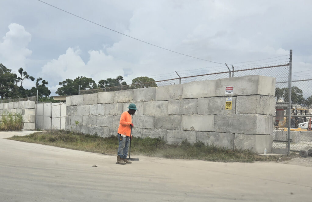 A worker sweeps concrete dust near a cingerblock wall.