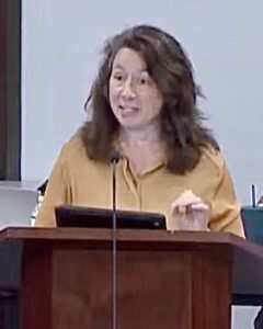 Elizabeth Ballard speaking at a podium.