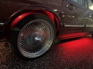 Close-up of a wheel of Lincoln with red underglow lights.