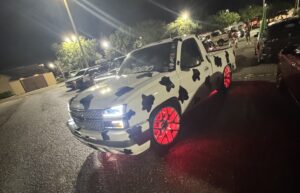 A truck with red wheel LEDs painted white with black spots like a cow.