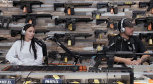 Bella Nelson Rittenhouse and Kyle Rittenhouse in a studio in front of a wall lined with guns.