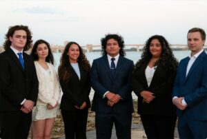 A lineup of students in formalwear near the coast.