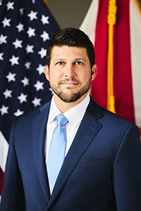 James Uthmeier in front of a U.S. flag.