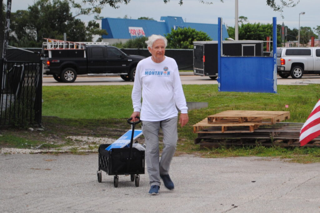 Matthew Montavon wearing a Matthew Montavon for Congress shirt and pulling a wagon containing a Matthew Montavon for Congress sign.