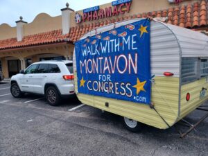 A poster that reads "Walk with me: Montavon for Congress" hung on the side of a parked trailer.