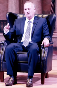 Richard Corcoran speaking while sitting on stage.